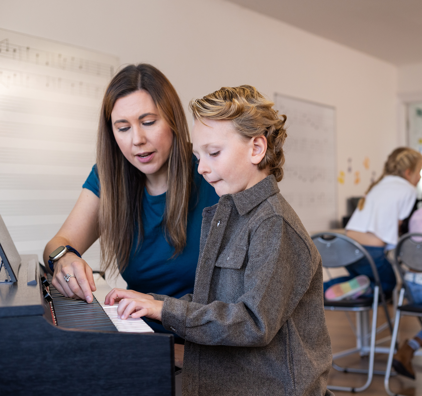 Teacher assisting young student at piano