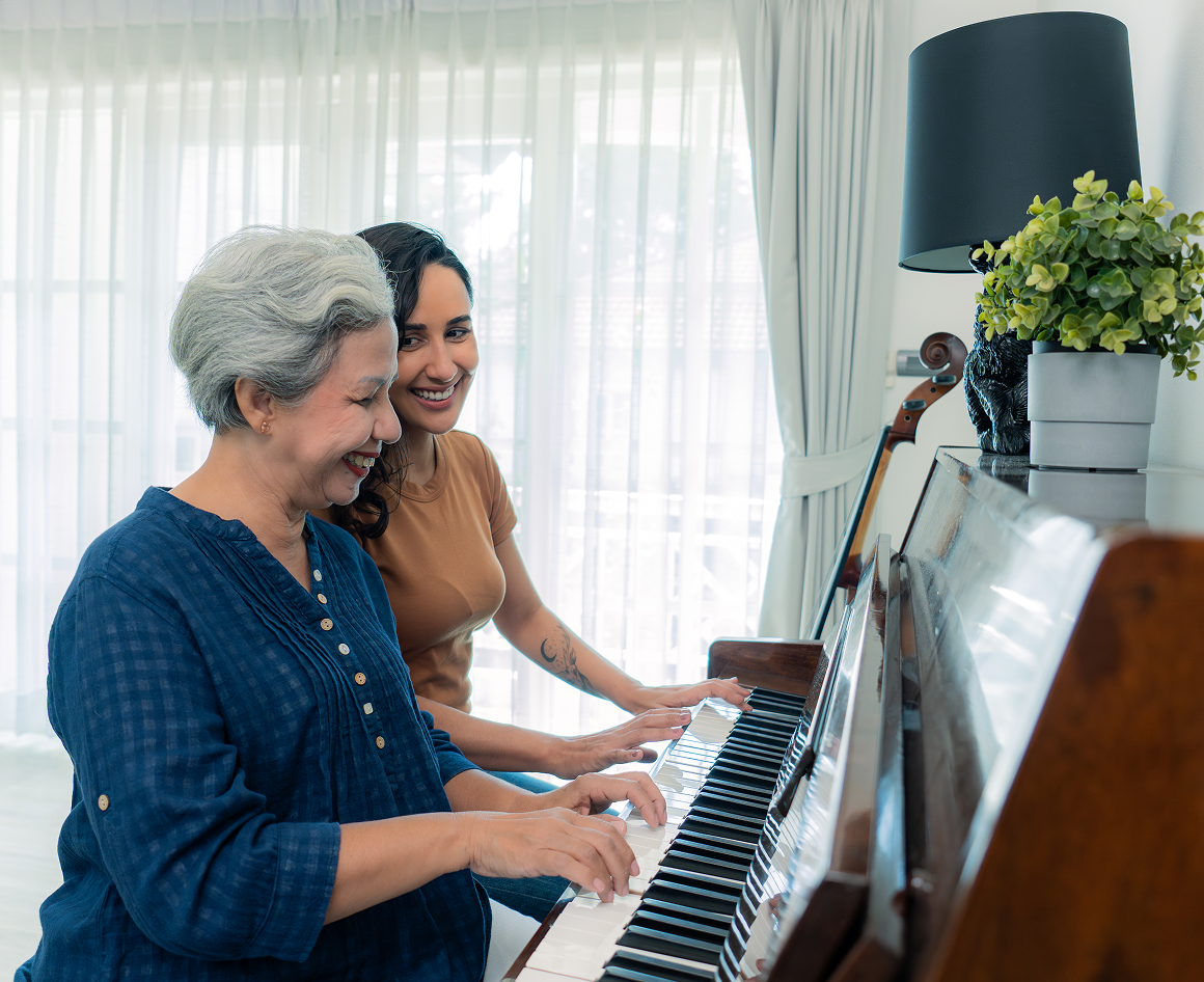 Women playing piano together, smiling