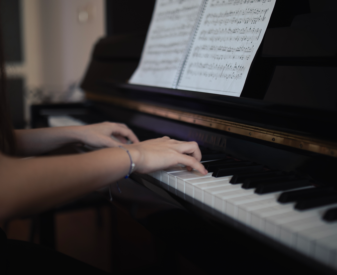 Hands playing piano with sheet music