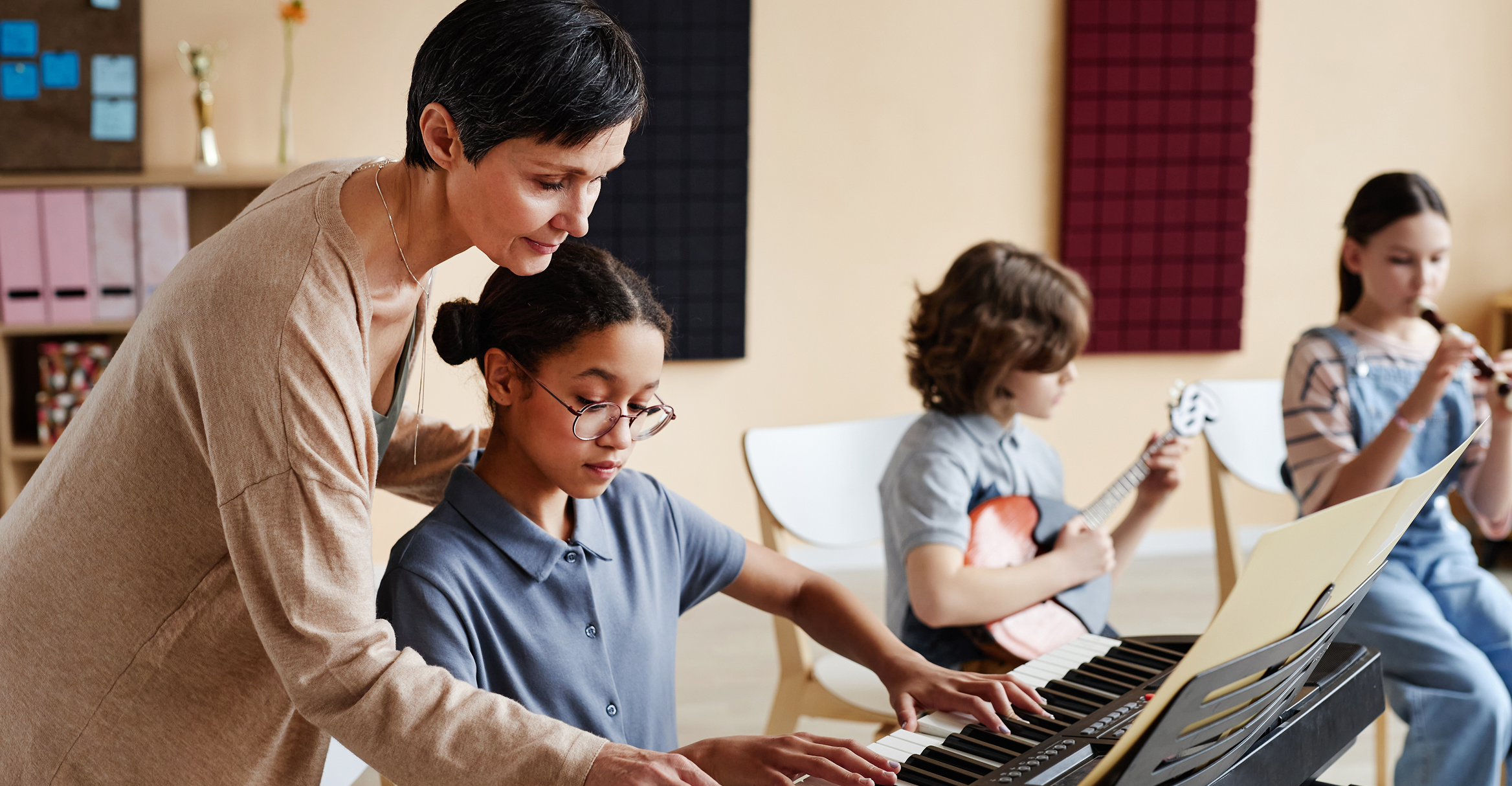Pupil learning piano with teacher's help
