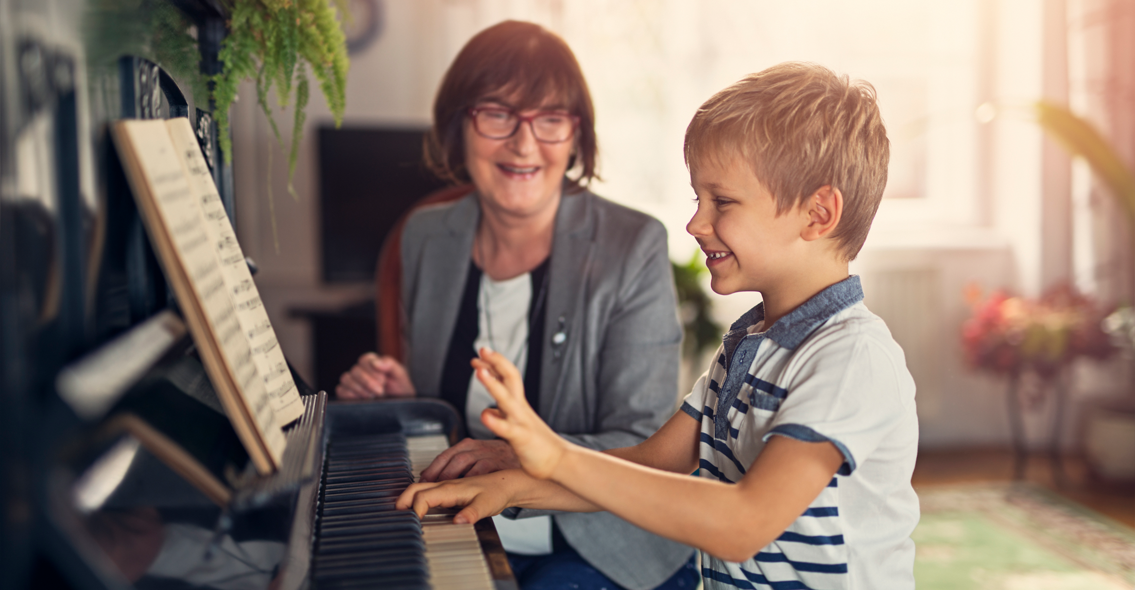 Child playing piano with smiling teacher